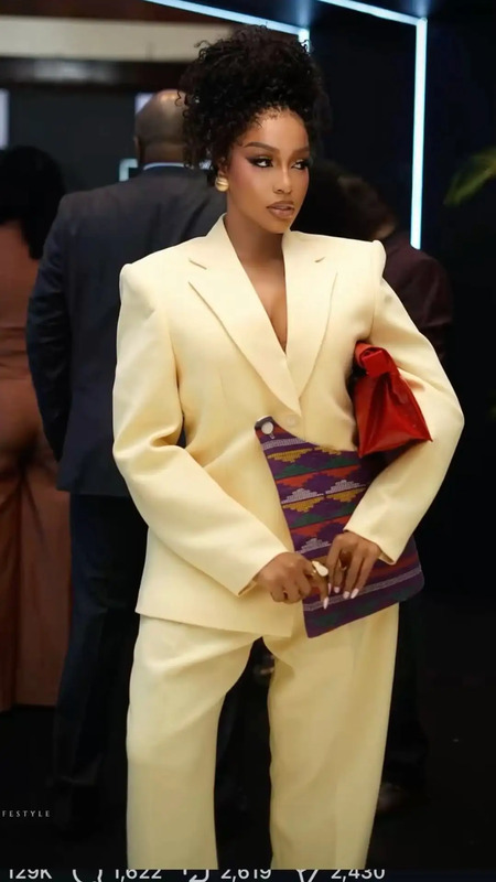 a woman in a white suit and red purse