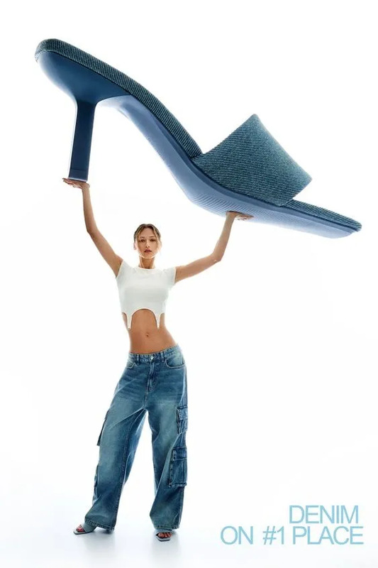 a woman in high heels is holding up a pair of blue shoes with her hands