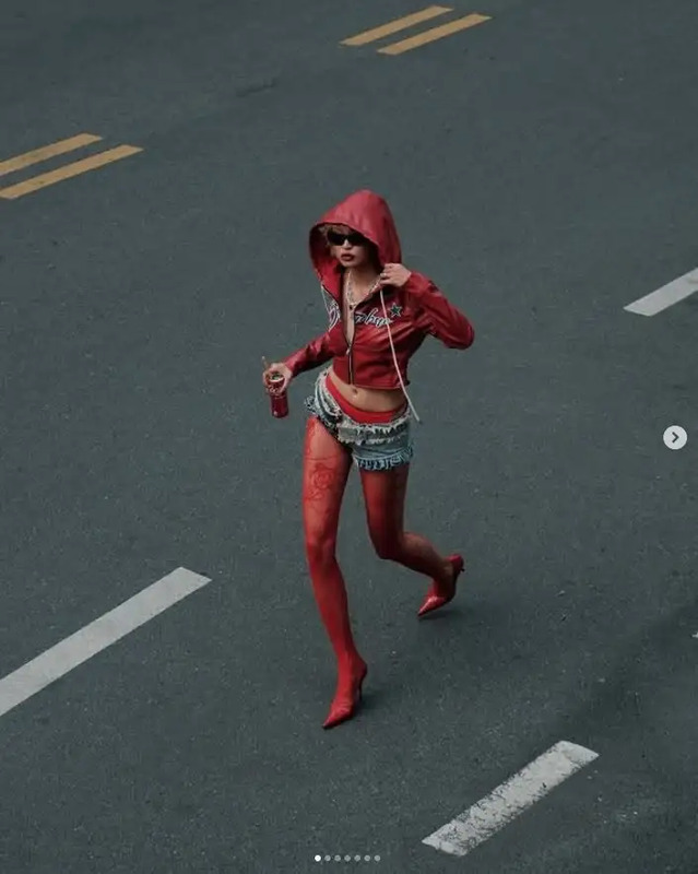 a woman in red hoodie and shorts running down the street with headphones on