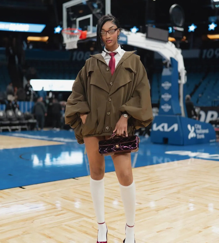 a woman standing on top of a basketball court wearing a skirt and jacket with white socks
