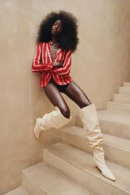 a woman in a red and white suit sitting on some steps with her legs crossed