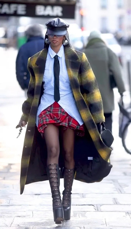 a woman walking down the street wearing a skirt and coat