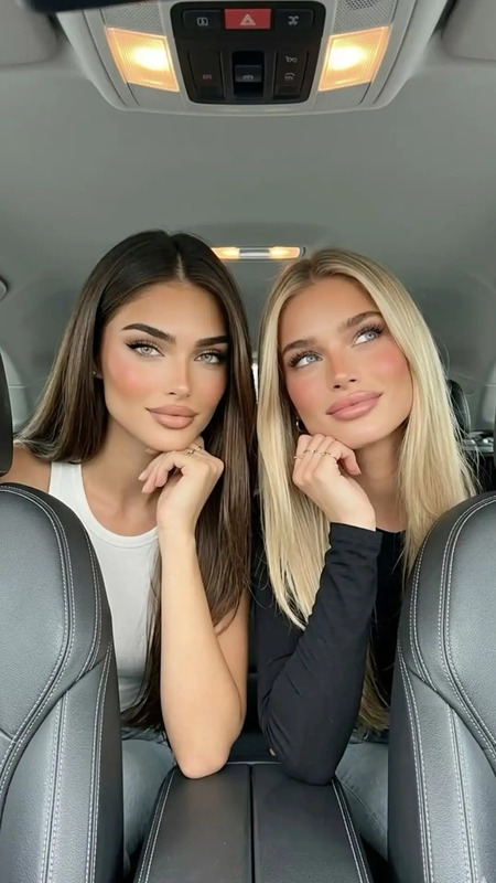 two beautiful women sitting in the back of a car