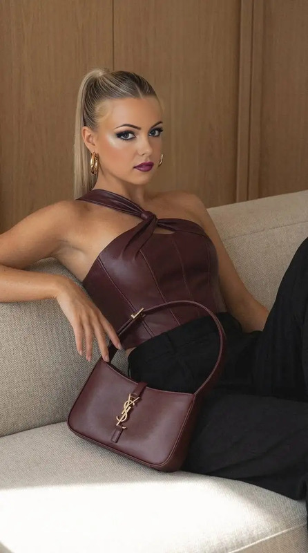 a woman is sitting on a couch with her handbag in front of her face