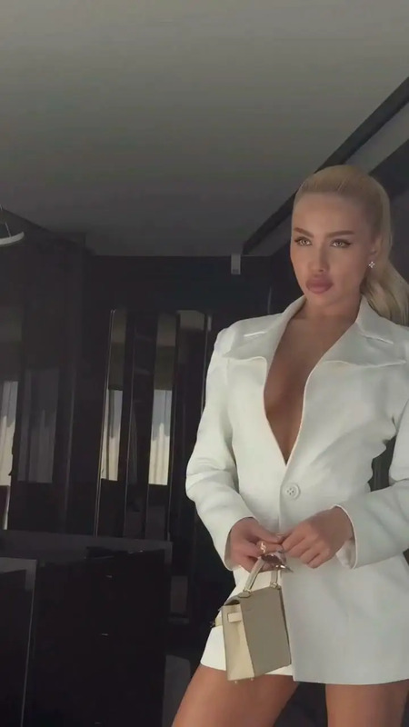 a woman in a white suit posing for the camera with her hand on her hip