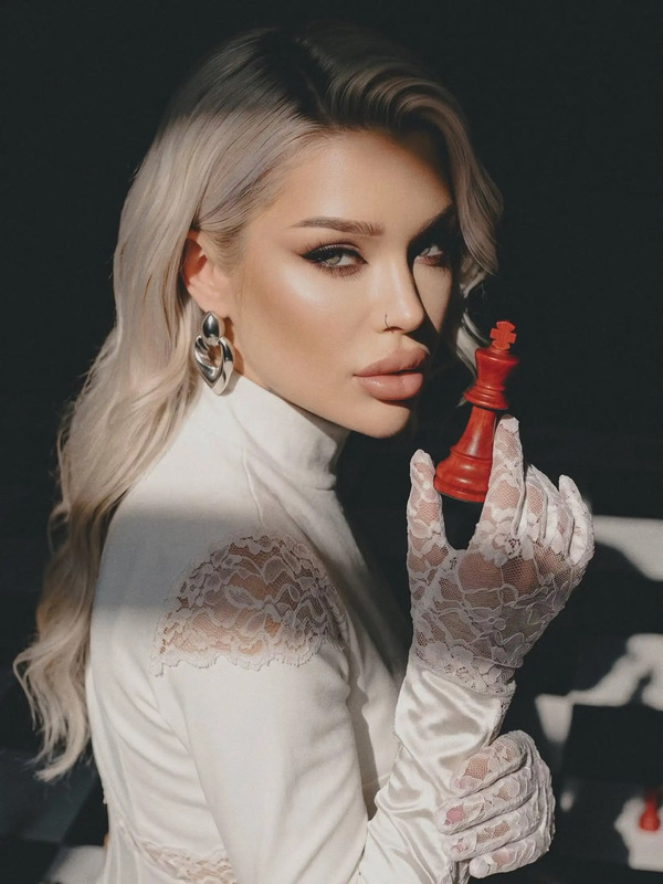 a woman holding a red object in her right hand and wearing white gloves with lace on it