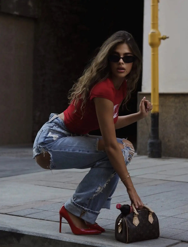 a woman kneeling on the ground with her hand in an open purse and wearing high heels