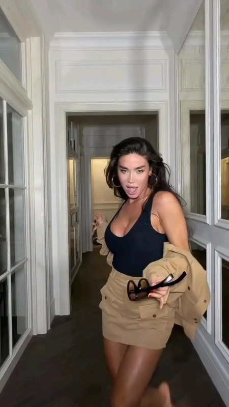 a woman is walking down the hallway with her hand in her pocket and holding a pair of scissors
