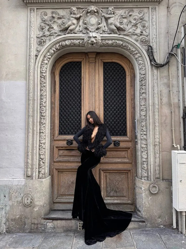 a woman standing in front of a door wearing a long black dress and high heels