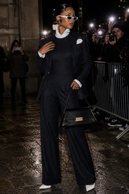 a woman in black and white outfit holding a handbag