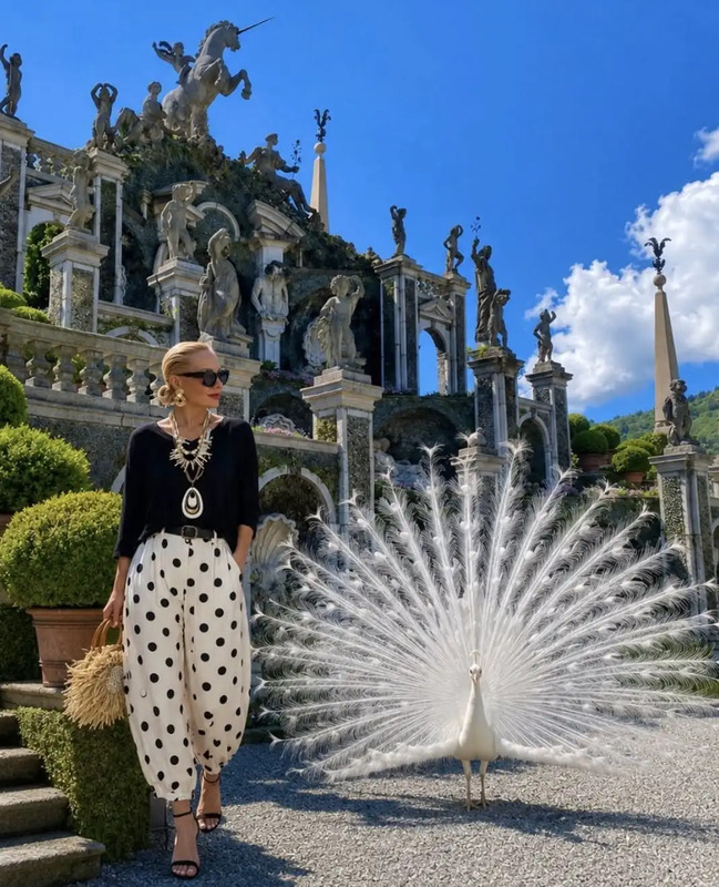 a woman standing next to a peacock in front of a building
