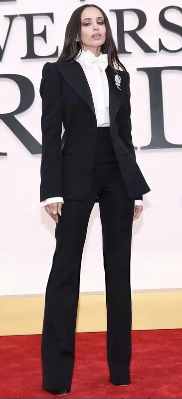 a woman in a black suit and white shirt on the red carpet at an event