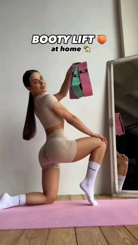 a woman in short shorts is doing yoga on a pink mat with a mirror behind her