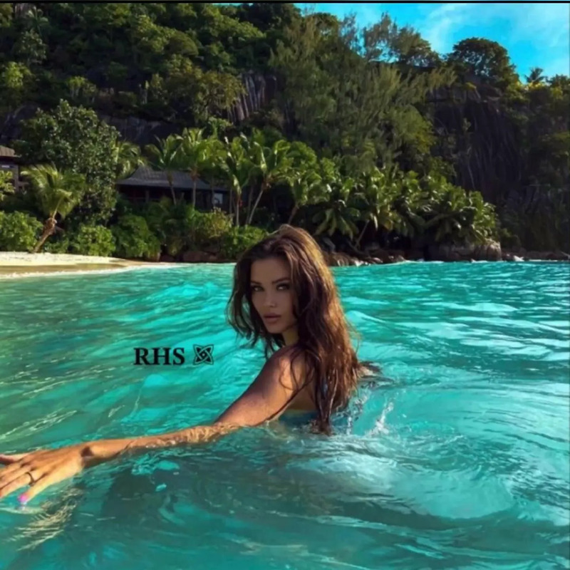 a woman is swimming in the ocean with her hand out to touch the water's surface