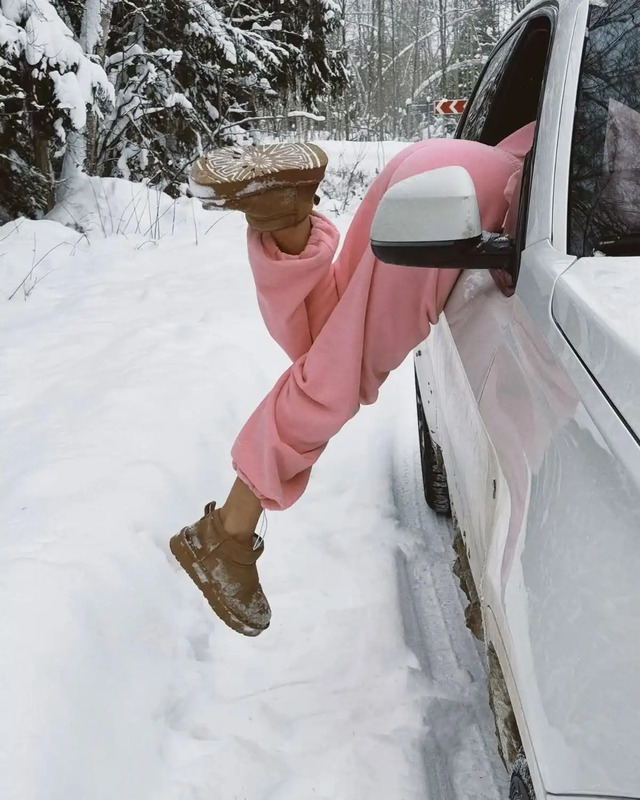 a woman in pink is leaning out the window of a white truck while wearing brown boots and a straw hat
