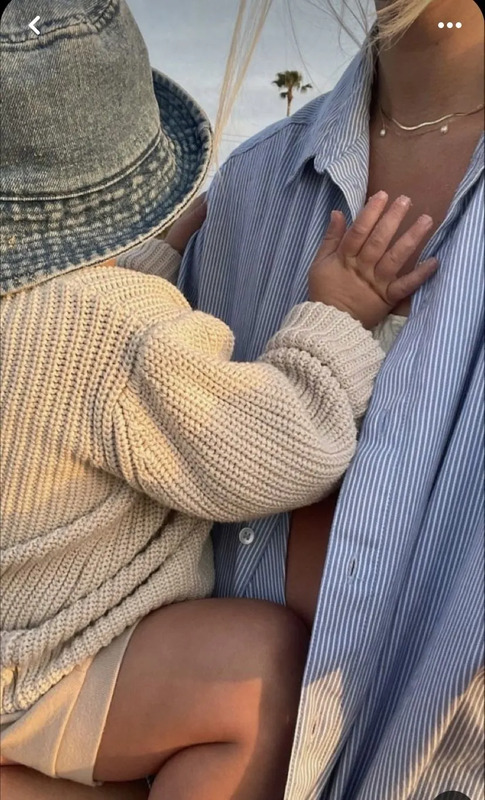 a woman holding a baby wearing a hat