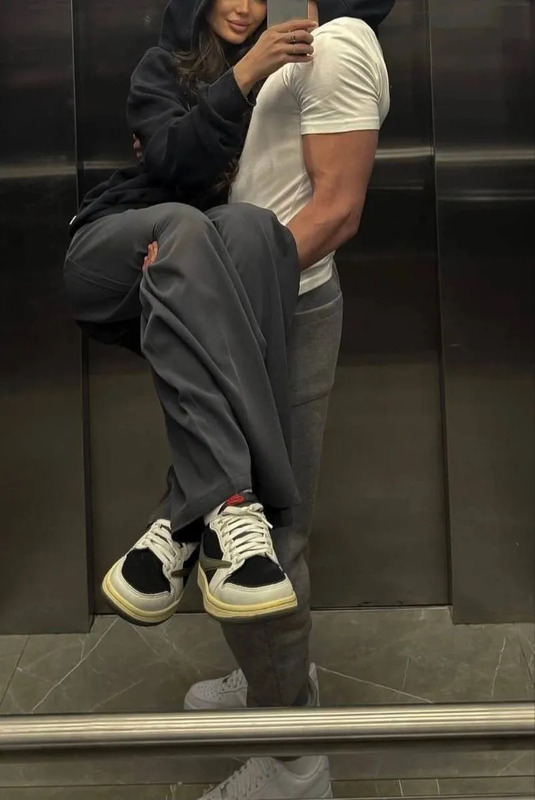 a man and woman taking a selfie in an elevator with their hands on each other's hips