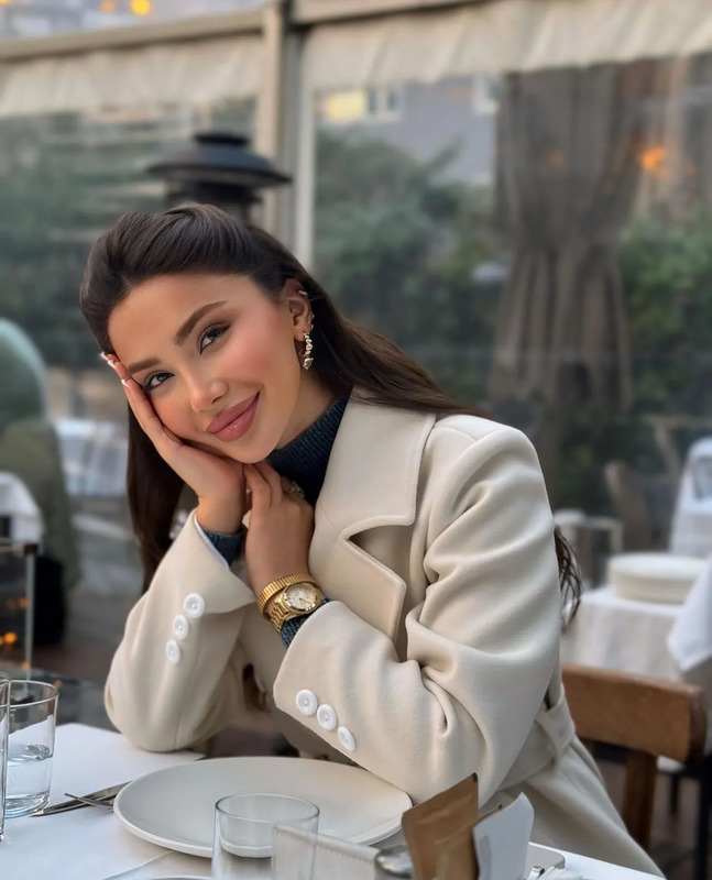 a woman sitting at a table with her hand on her chin and looking off to the side