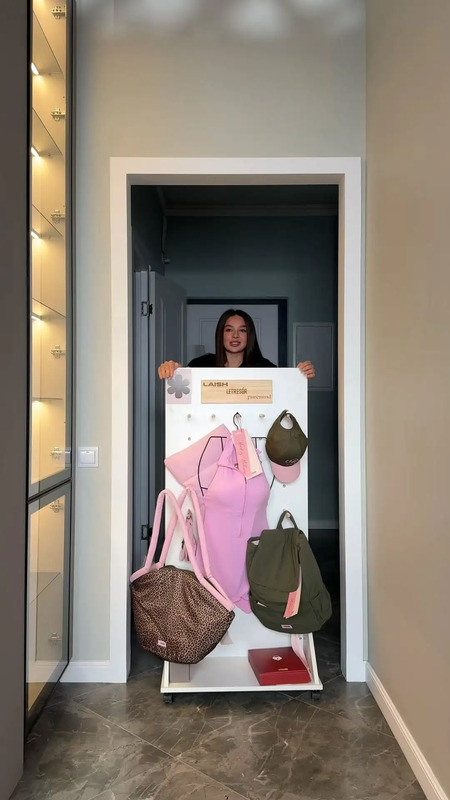 a woman standing behind a white shelf with purses and bags on top of it
