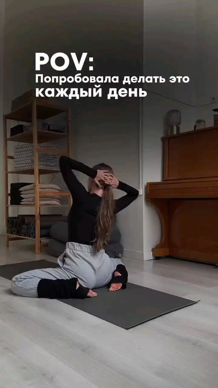 a woman sitting on top of a yoga mat in front of a wooden desk and piano
