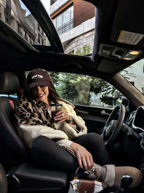 a woman sitting in the driver's seat of a car holding a cell phone