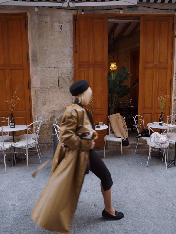 a woman is walking down the street with a coat over her head and shoes on