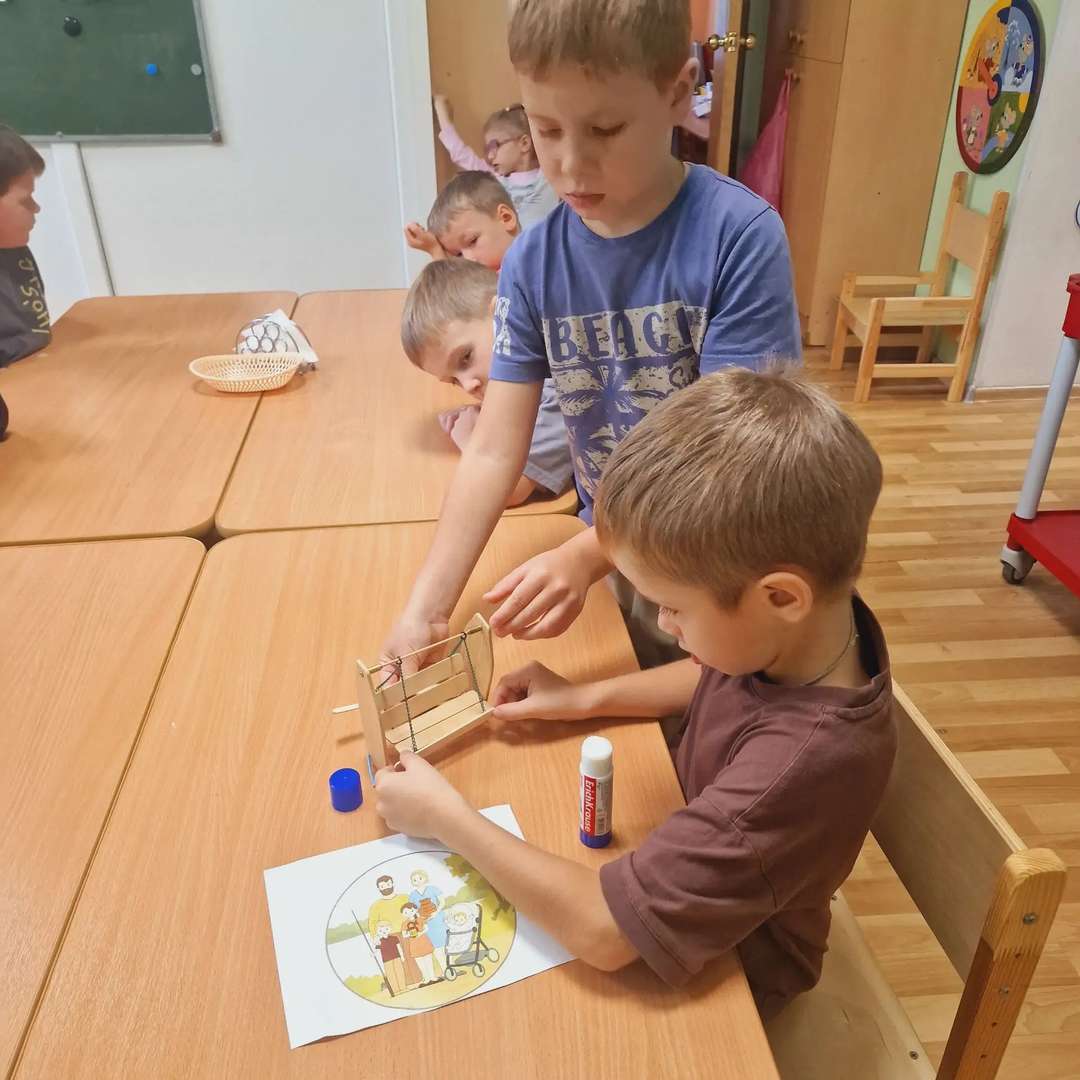 Когда мы начали обустраивать наш парк - решили, что обычные скамейки — это слишком скучно. Нашим пациентам нужно не просто отдыхать, а радоваться! Поэтому мы с ребятами придумали нечто совершенно необыкновенное. Мы взяли деревянные палочки и картон, но сделали из них не простые лавочки, а настоящие качели!
Только представьте, как это здорово! Мы аккуратно соединяли детали, чтобы сиденья могли по-настоящему качаться. Я была в таком восторге, когда у нас получилось закрепить картонные спинки на палочках-опорах. Я прыгала от радости, проверяя, как плавно они двигаются! Ведь это так важно — чтобы после визита к врачу у человека поднялось настроение, а на качелях всегда хочется улыбаться.