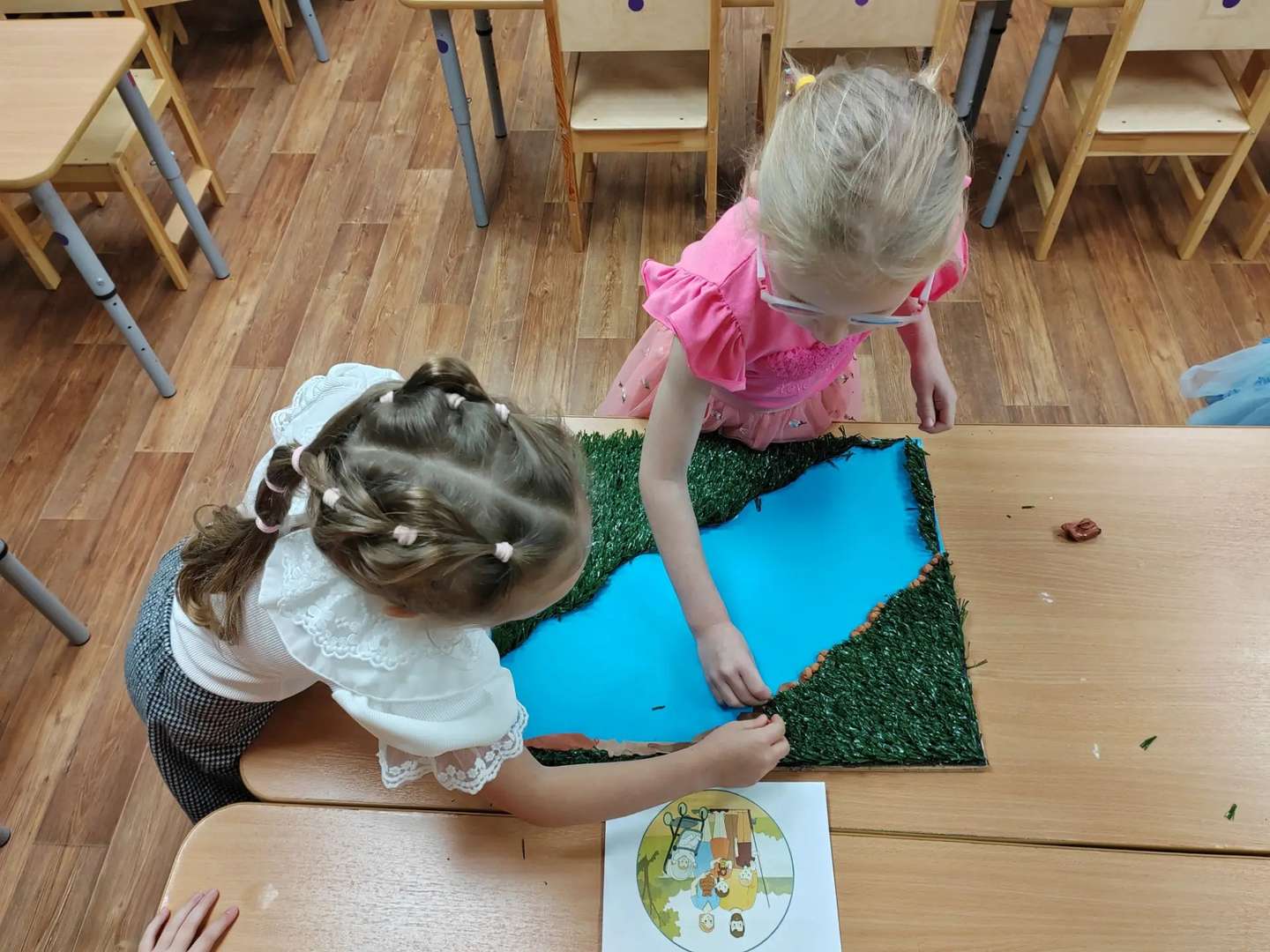 Чтобы наша река была особенно красивой и никогда-никогда не выходила из берегов, мы придумали отличную хитрость! Мы решили по краям разложить крепкие камушки. И, конечно же, мы тоже слепили их сами из пластилина! 🪨
Мы выбирали серый, коричневый и даже черный пластилин, катали из него шарики и делали их разной формы, чтобы они были похожи на настоящие карельские валуны. А потом аккуратно, один за другим, выкладывали их вдоль берега нашей речки. Получилась настоящая защитная стена и невероятная красота! С такими каменными берегами нашей речке не страшны никакие наводнения, вся водичка останется на своем месте. 🌊
Когда мы закончили, бережок стал выглядеть просто волшебно, совсем как те каменистые берега, которые я видела в Карелии. Ребята из группы очень хвалили нашу задумку, ведь теперь наш маленький карельский мир стал еще более защищенным и живописным! 🎈🪨