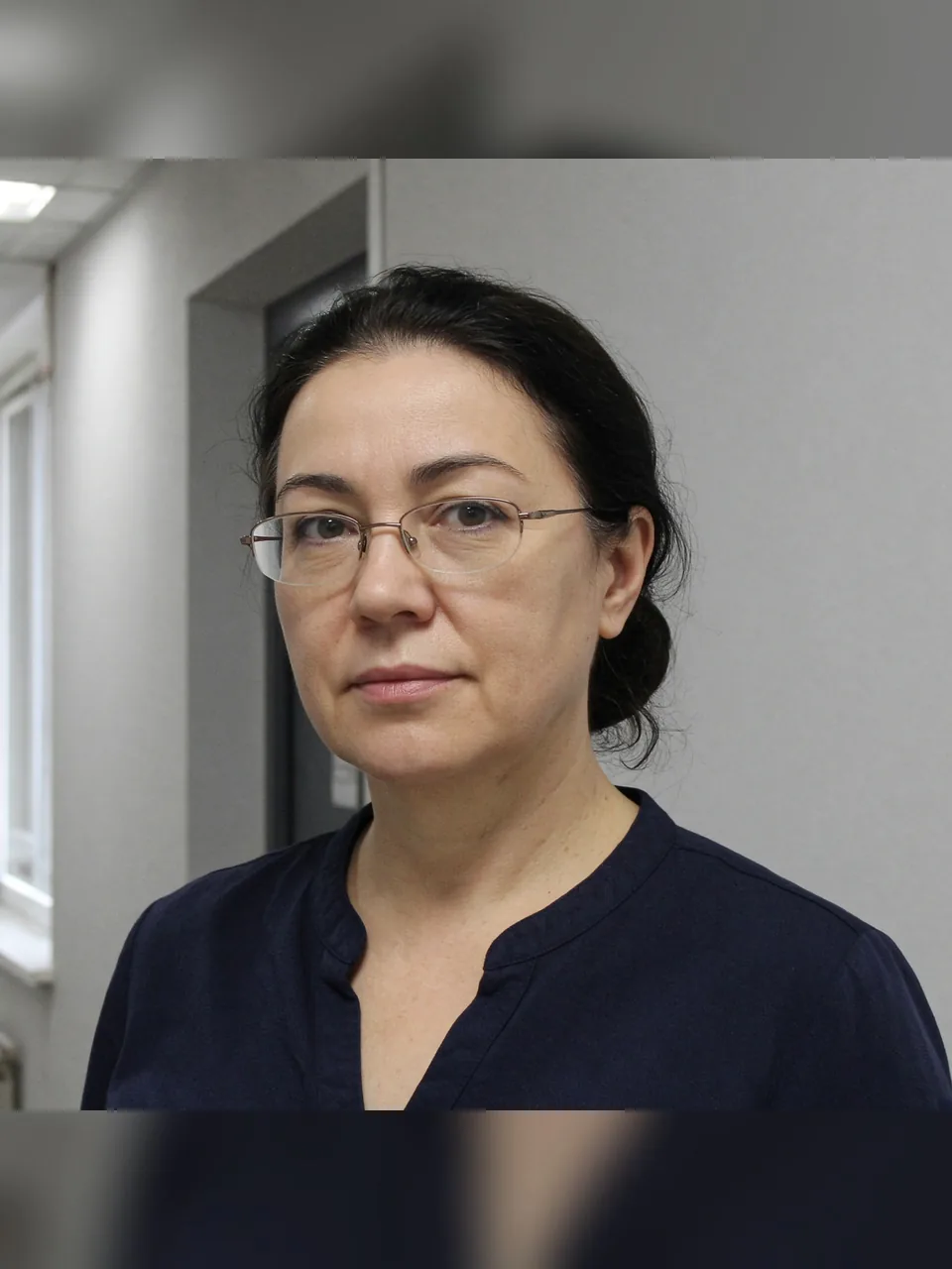 Женщина в очках в офисном коридоре, квадратный кадр
