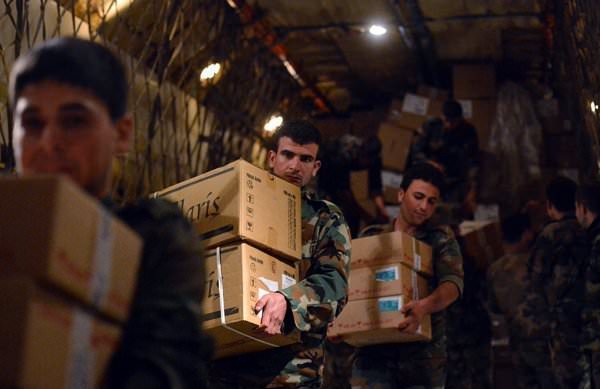 Сирийские военнослужащие разгружают коробки с гуманитарной помощью из России с борта самолета МЧС РФ