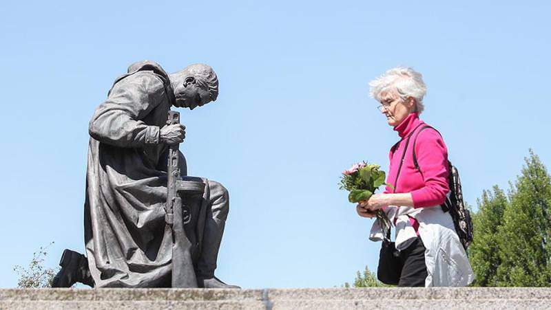 Женщина с букетом напротив статуи советского солдата на военном мемориале в Трептов-парке, Берлин