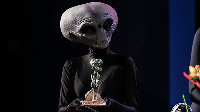 Пришелец со статуэткой «Грустный рептилоид» на вручении антипремии «Почётный академик ВРАЛ» 
