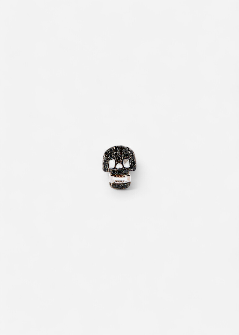 Piercing in the form of a skull made of gold with a black diamond