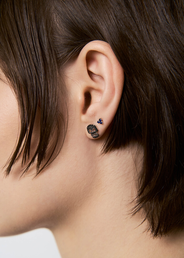 Piercing in the form of a skull made of gold with a black diamond