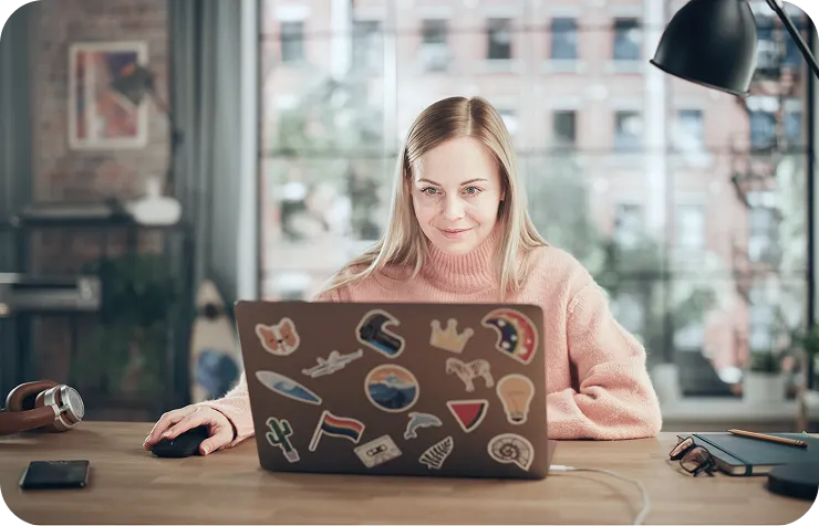 Девушка сидит за столом перед ноутбуком