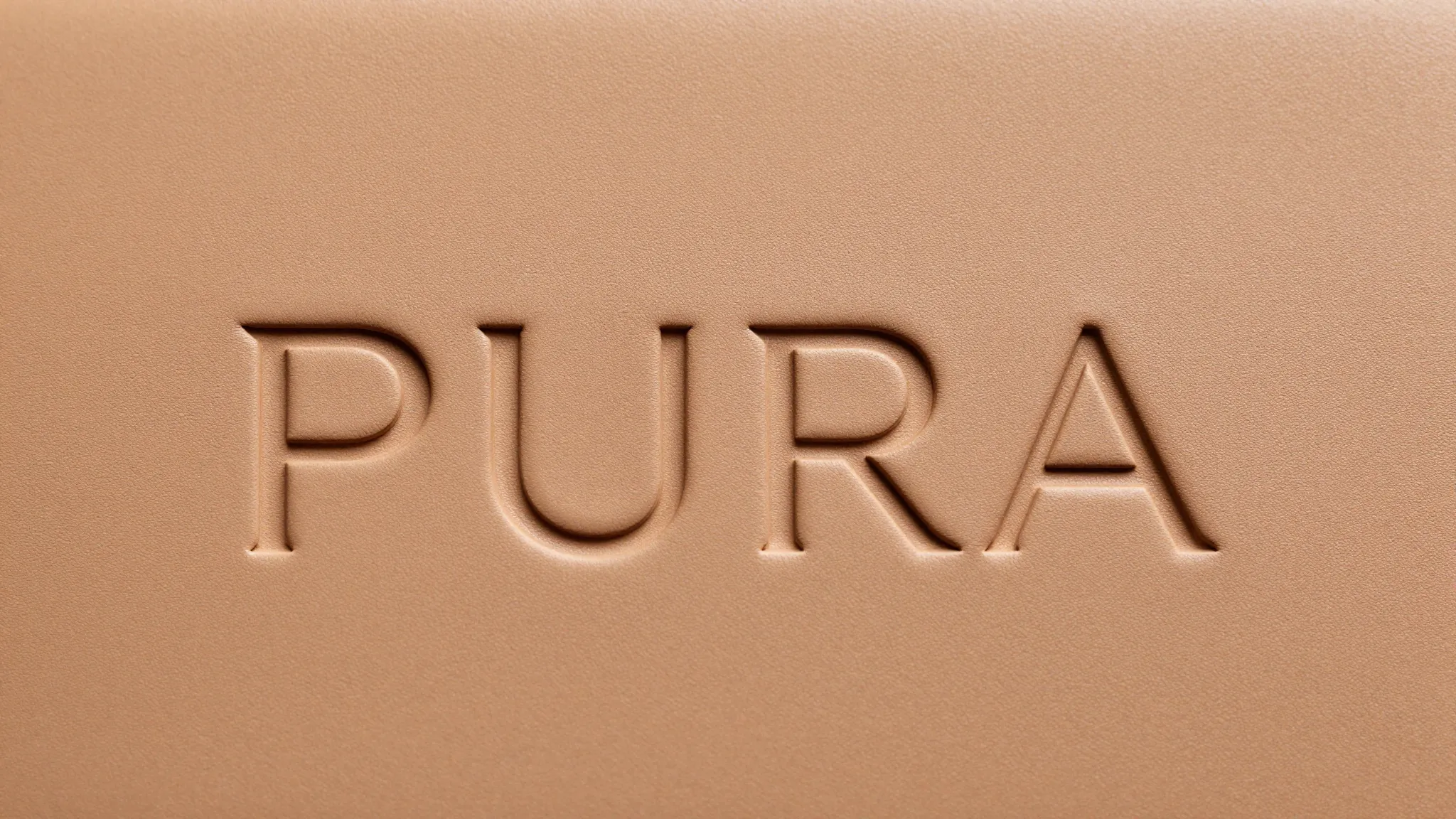 Elegant minimalist logo 'PURA' embossed on a piece of high-q...
