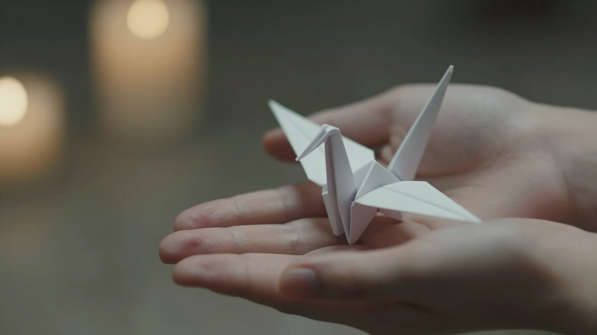Close-up of human hands gently holding delicate white origam...