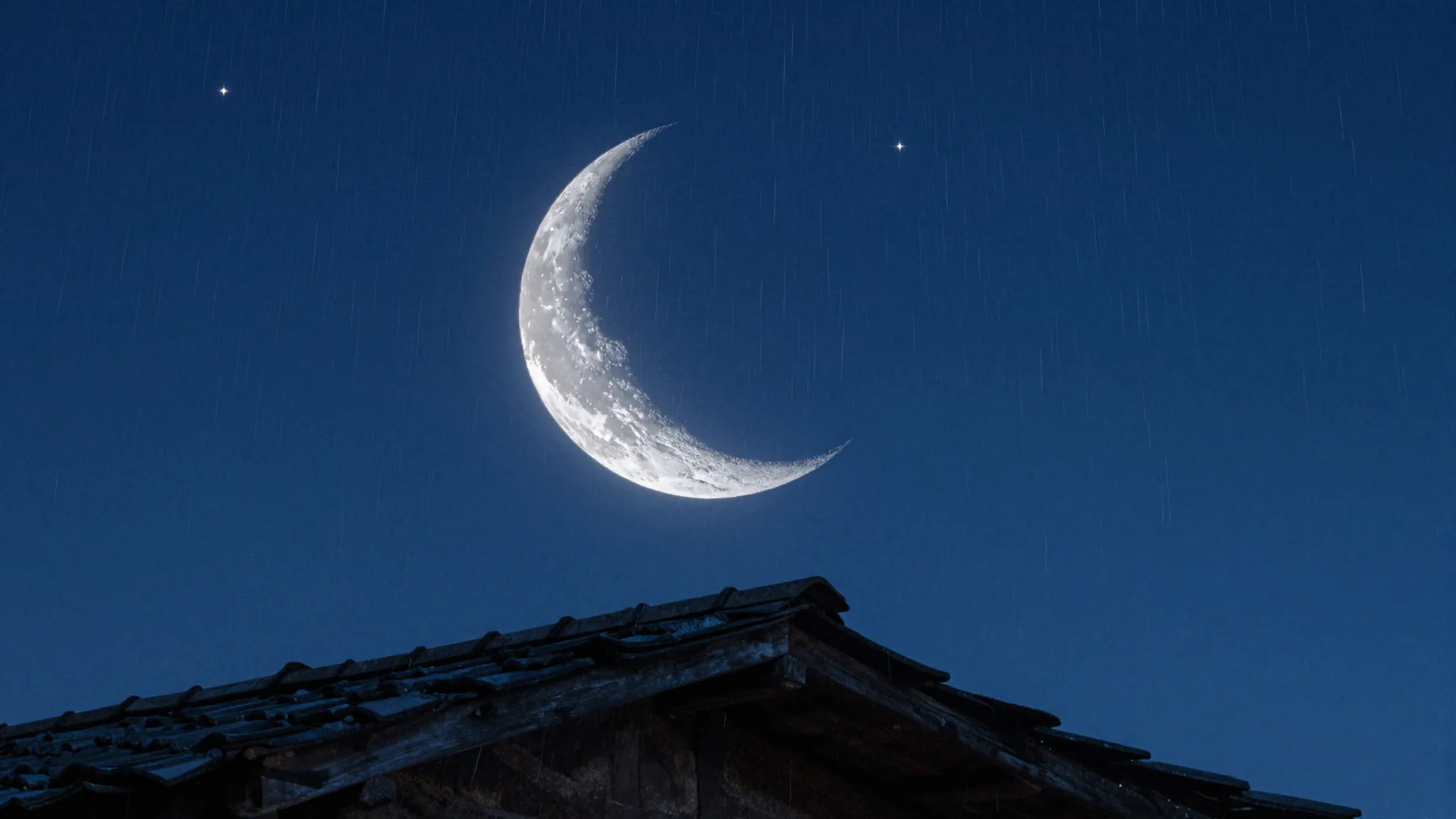 A thin crescent moon hanging directly over a rustic rooftop ...