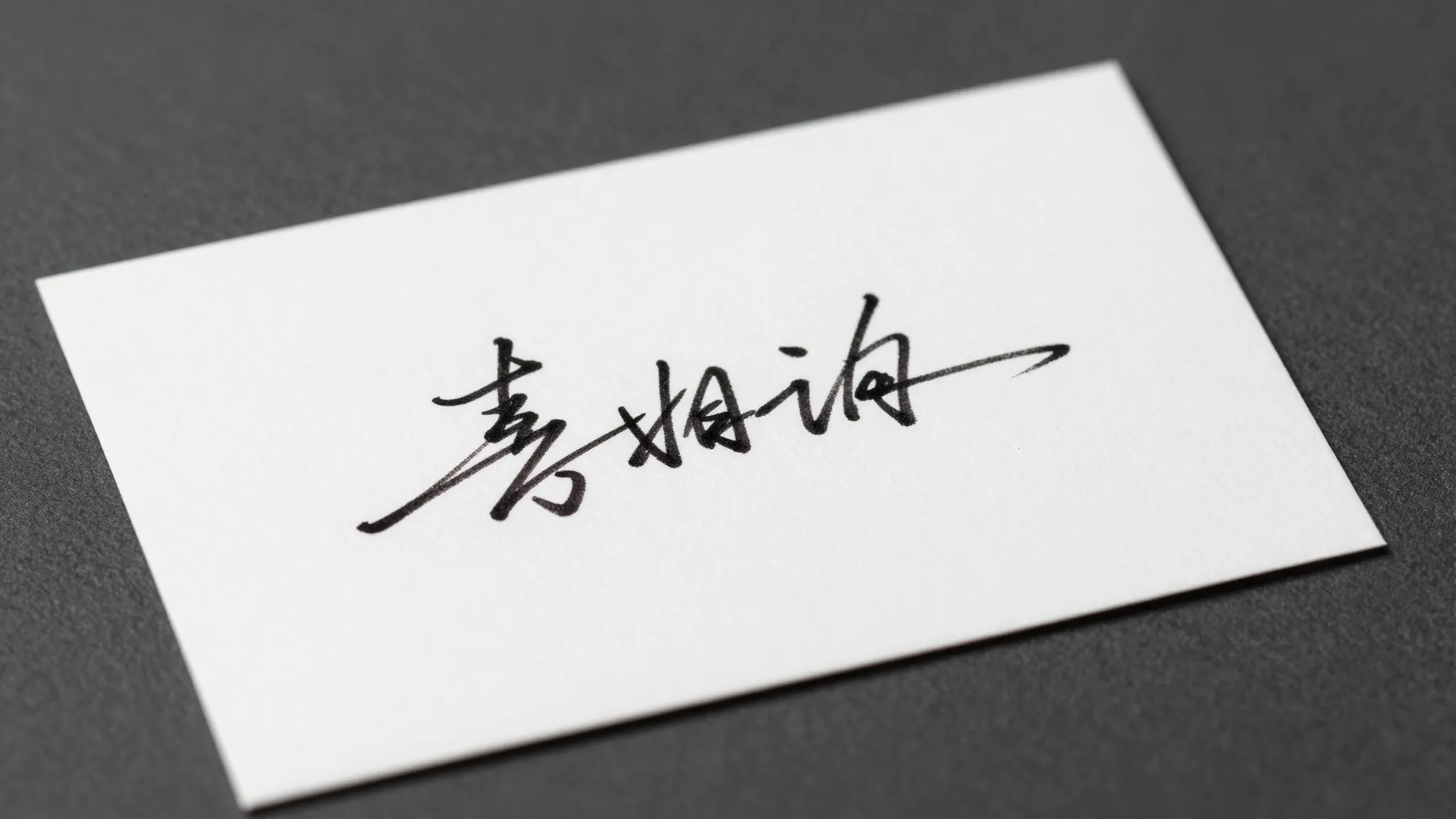 A minimalist calligraphic signature on a white business card...
