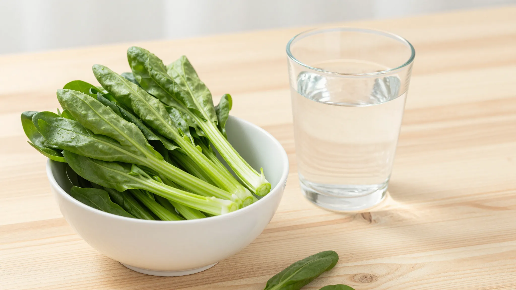 A bowl of fresh green vegetables and a glass of clean water ...