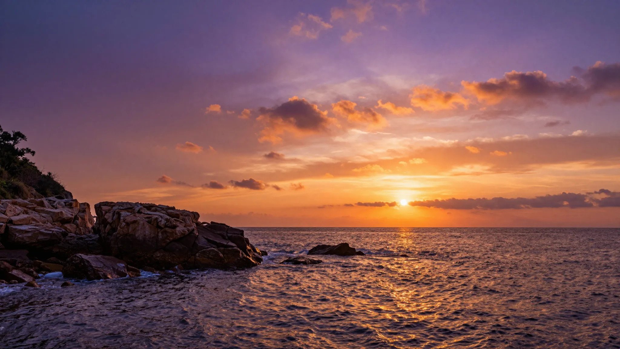 Bright orange and violet sunset over a rocky coastline, spar...