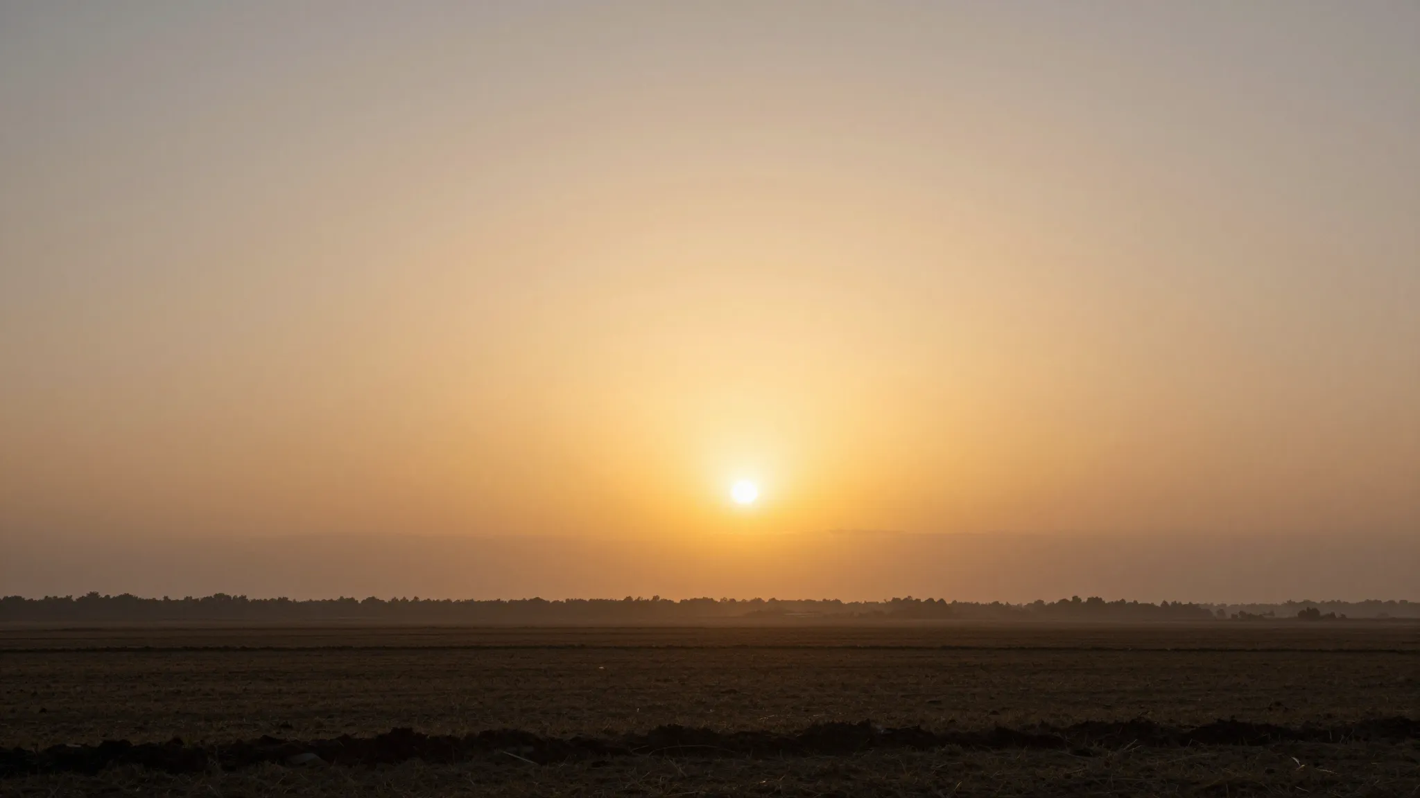 A warm and peaceful sunrise over a calm landscape, golden li...