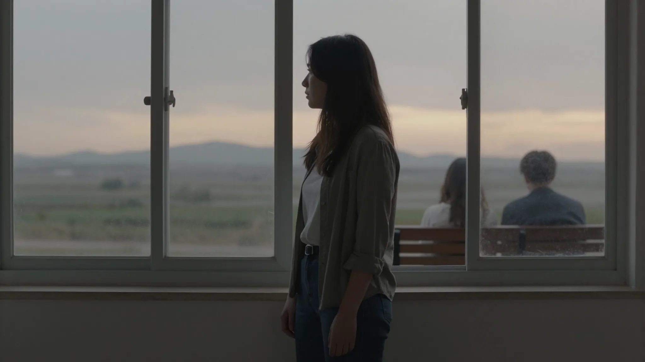 A woman in her thirties standing by a window during a grey s...