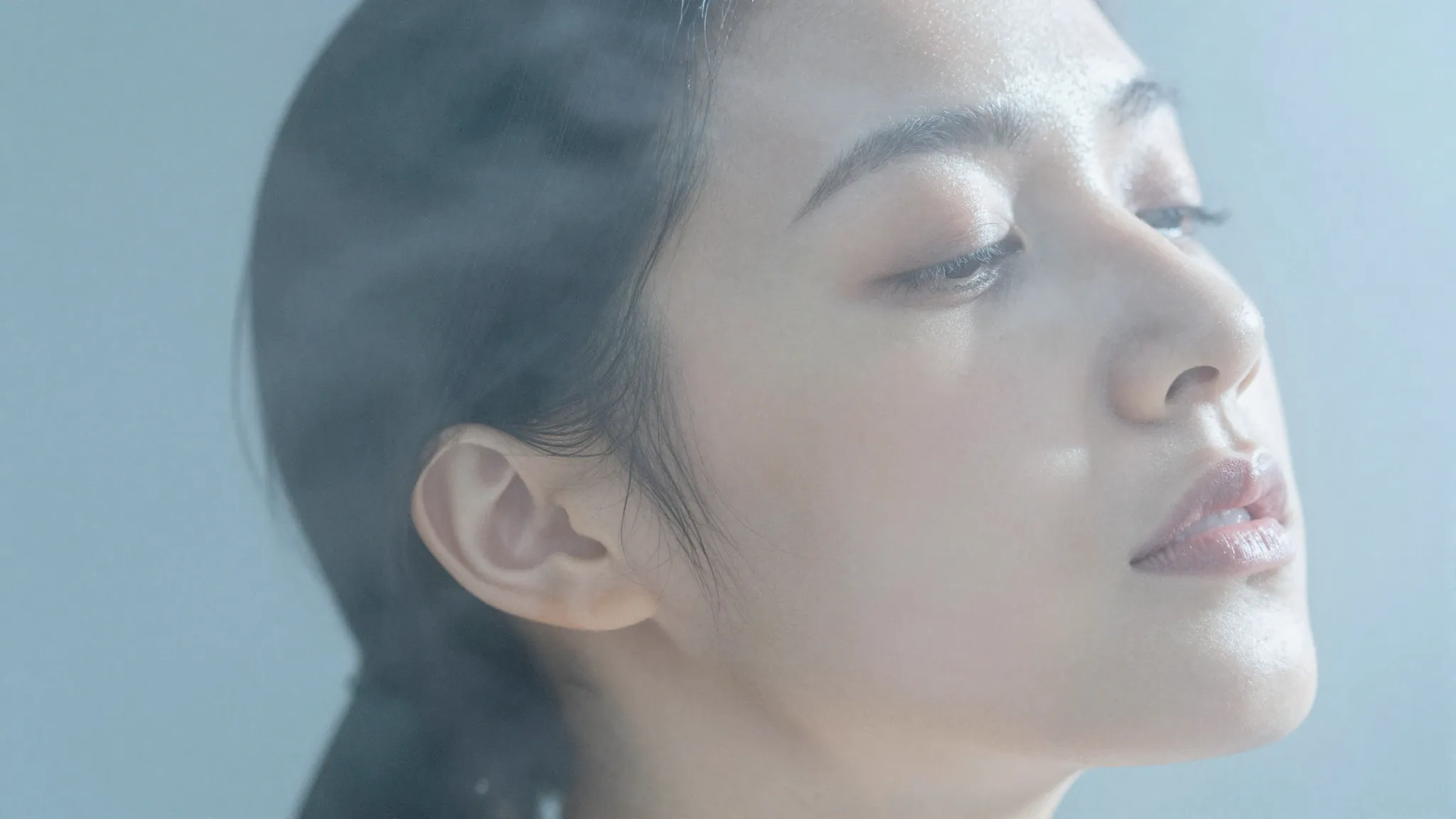 A person feeling refreshed by a gentle mist of water, calm f...