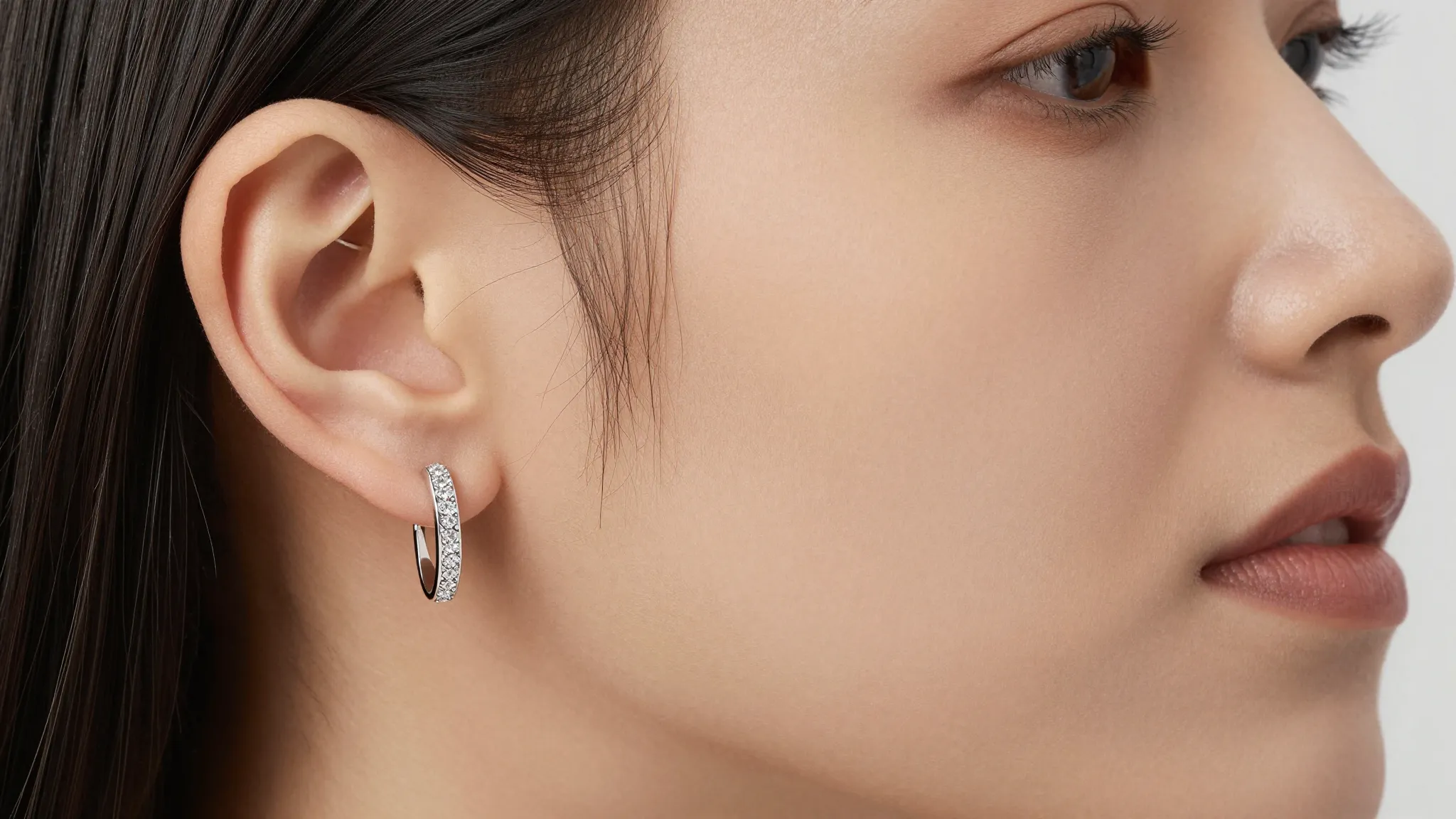 A close-up of a woman's ear wearing an elegant silver ear cl...