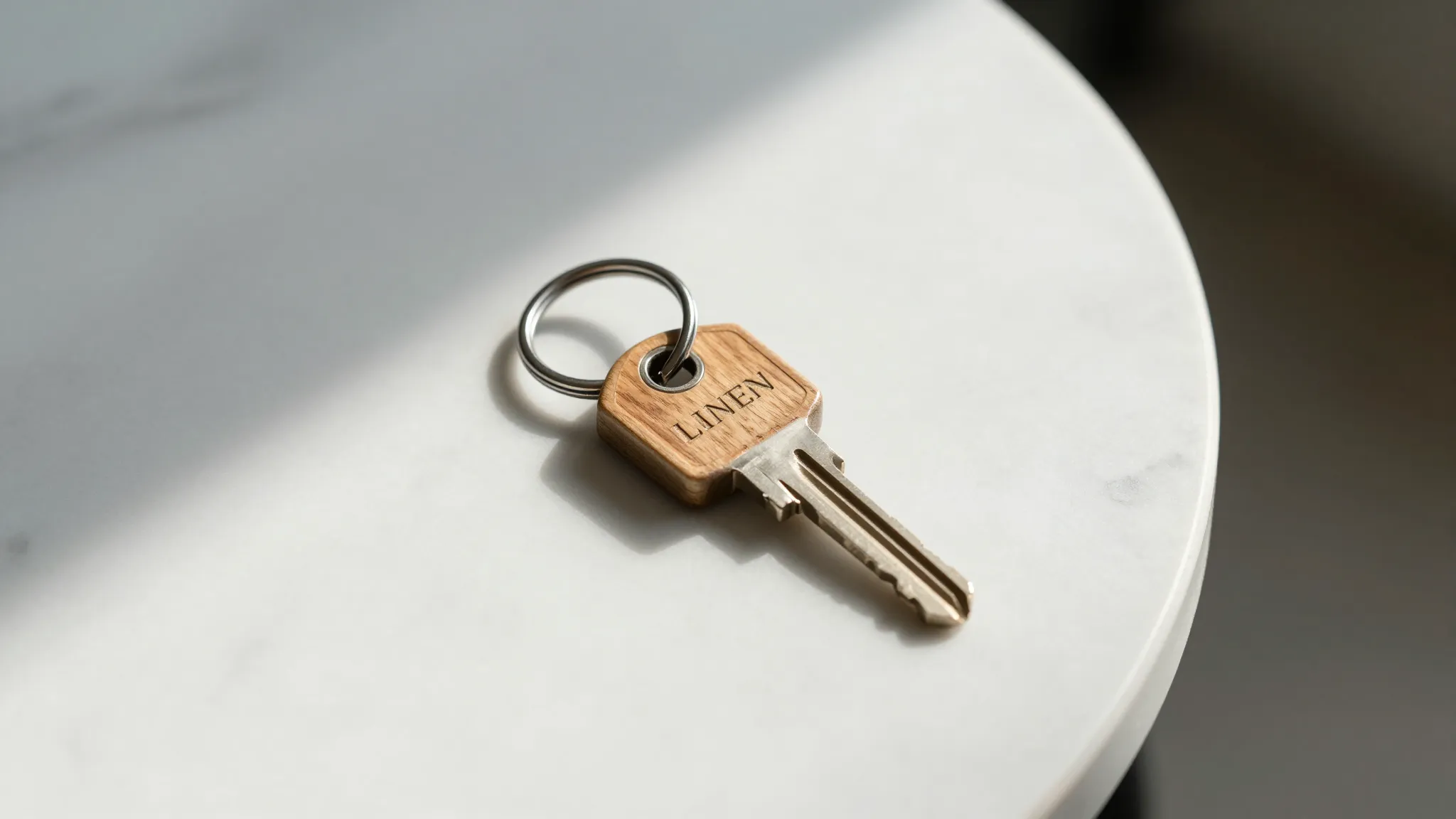 A modern minimalist key with a wooden keychain on a white ma...