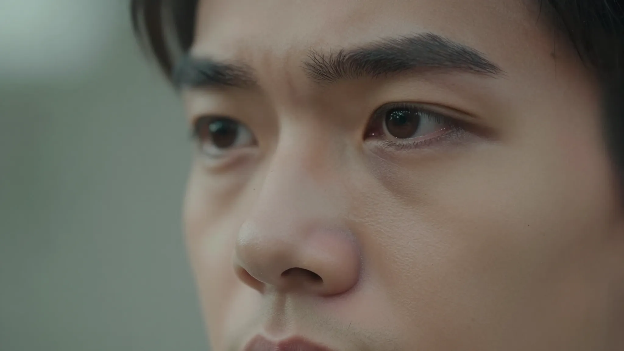 A close up of a person's face looking into the distance with...