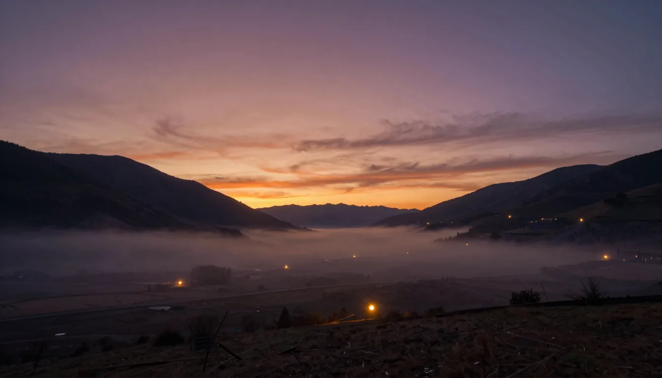A wide landscape of a sleepy valley at dusk. The sun is disa...