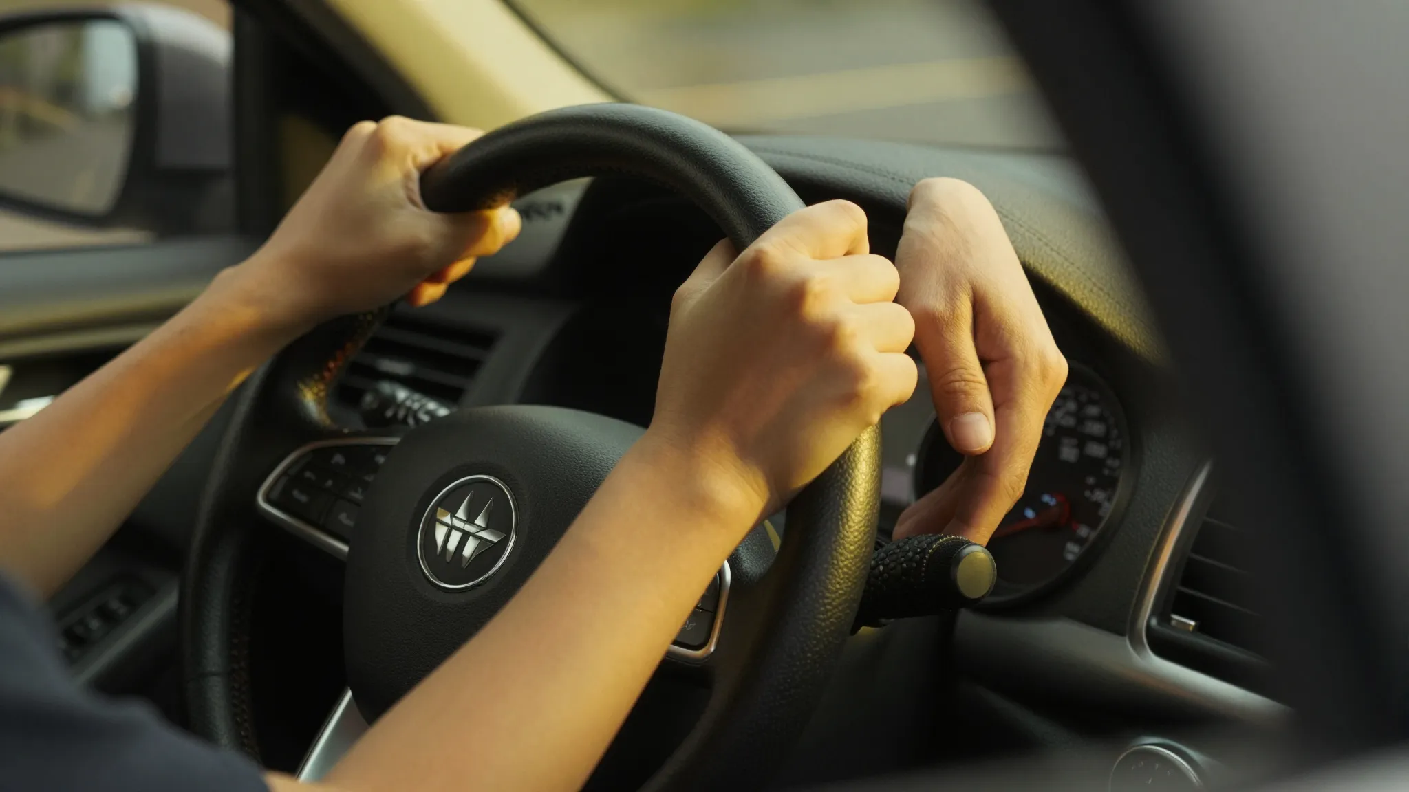 Close-up of a student's hands gripping a steering wheel tigh...