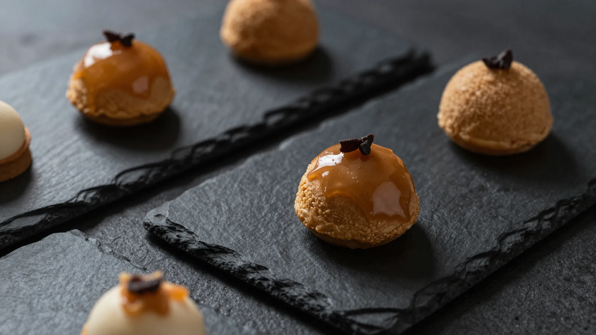 Close-up of gourmet desserts on black matte stone boards, na...